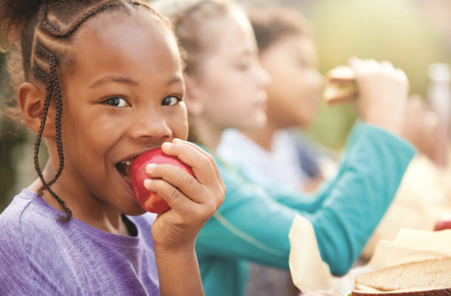 Young girl eating an apple at lunch